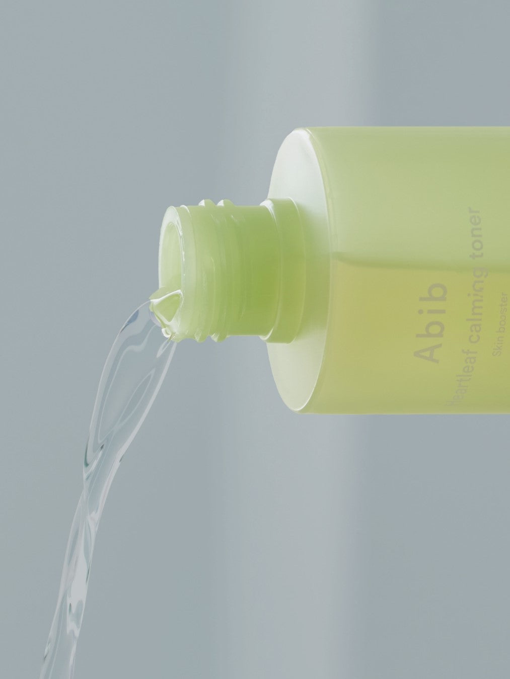 Close-up of Abib Heartleaf Calming Toner bottle pouring its lightweight, watery texture against a soft neutral background.