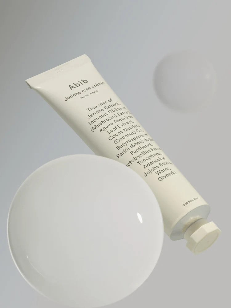The Abib Jericho Rose Crème tube, showcasing a minimalist design and key ingredients, floating against a soft-focus bubble backdrop, emphasizing hydration and nourishment.