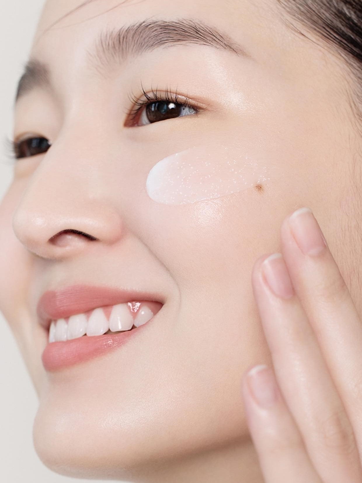 A model gently applying Aestura Atobarrier 365 Cream to the cheek, showcasing a close-up of the ceramide capsules in the texture.
