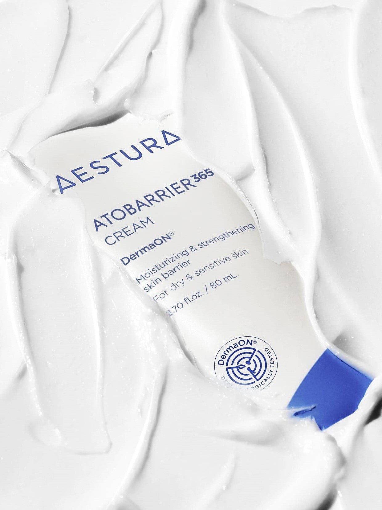 A close-up of the Aestura Atobarrier 365 Cream tube partially submerged in thick white cream, highlighting its moisturizing properties.