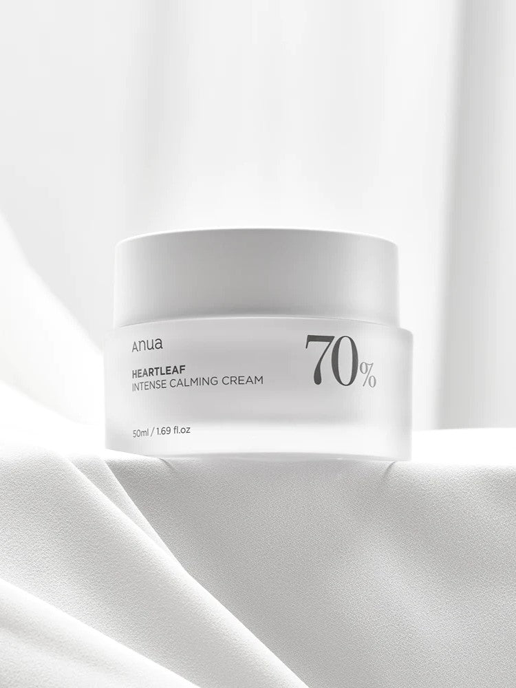 A white jar of Anua Heartleaf Intense Calming Cream, labeled with 70% Heartleaf, resting on a soft, textured white surface.