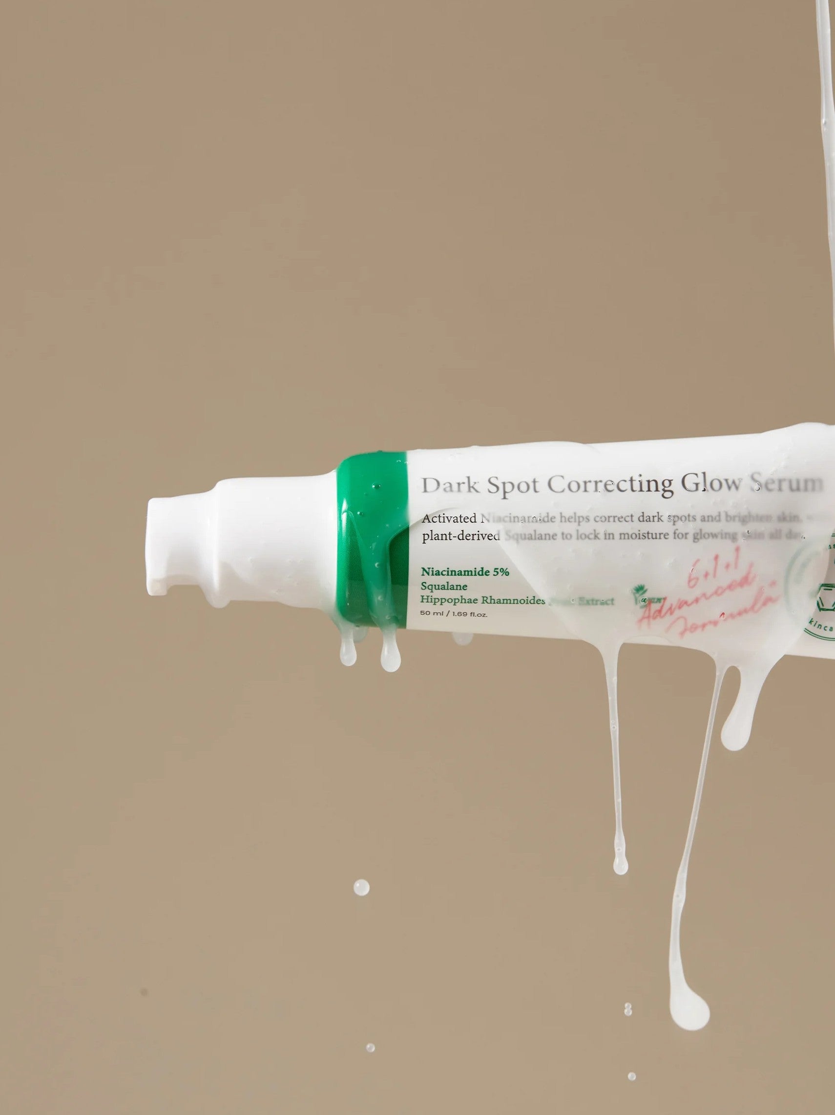 A tube of Axis-Y Dark Spot Correcting Glow Serum drips, showcasing its lightweight texture against a neutral background.