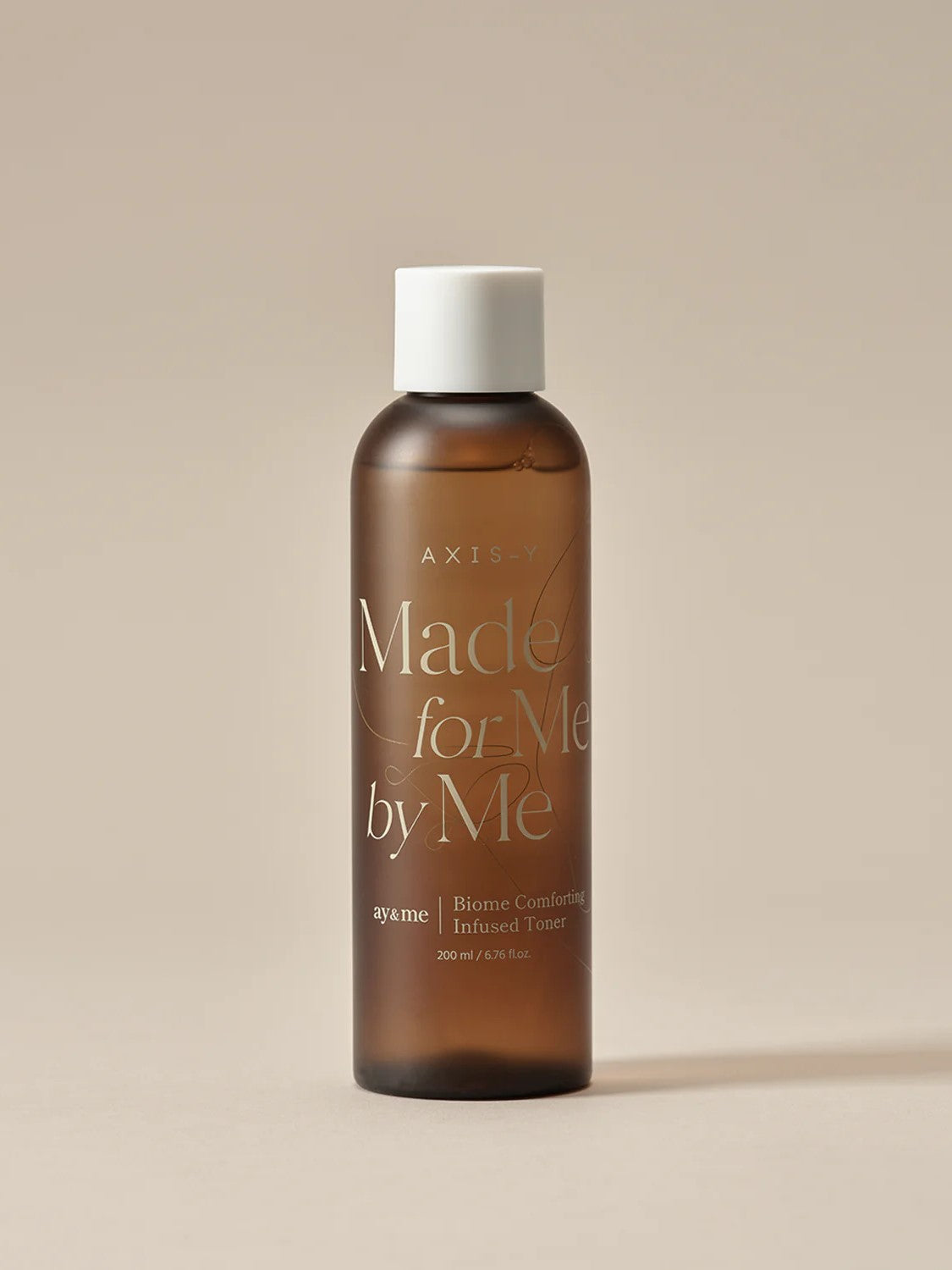 Brown glass bottle of AXIS-Y Biome Comforting Infused Toner labeled 'Made for Me by Me,' set against a neutral background.