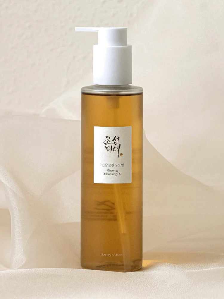 Amber bottle of the Beauty of Joseon Ginseng Cleansing Oil with a white pump top, set against a soft, neutral background, featuring a label with the brand logo in Korean text.