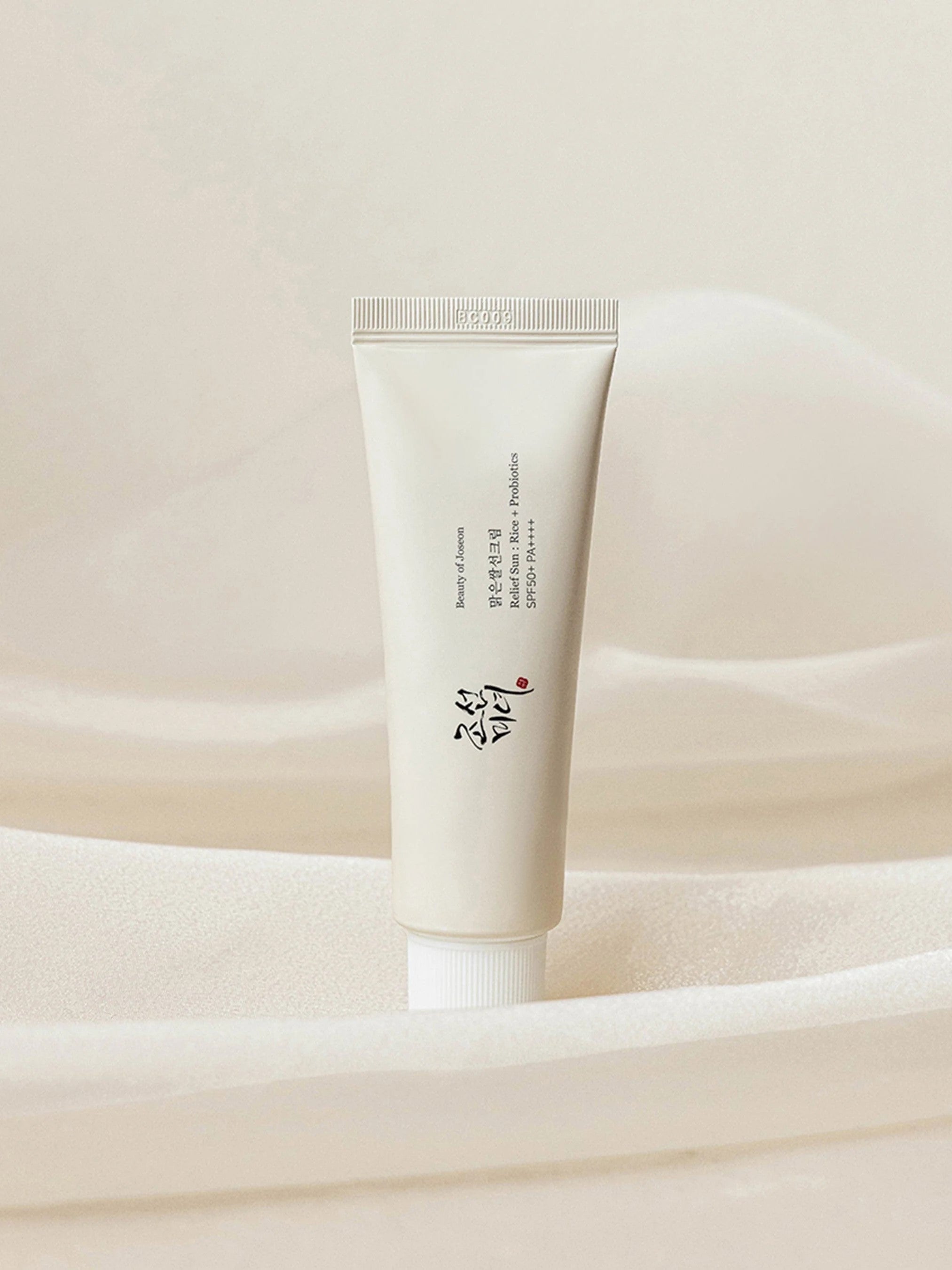 Beauty of Joseon Relief Sun: Rice + Probiotics placed against a soft, textured background, highlighting its elegant design and dual benefits of nourishing skincare and sun protection.