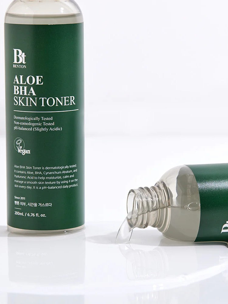 Close-up of Benton Aloe BHA Skin Toner with liquid spilled beside the bottle, showing its light gel-like texture and sleek packaging.