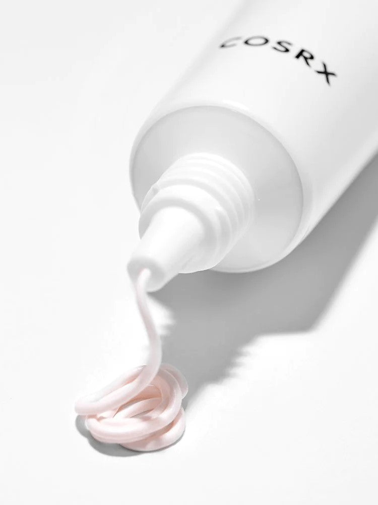 A tube of Cosrx Ultimate Spot Cream with a creamy pink lotion swirl, set against a clean white background.