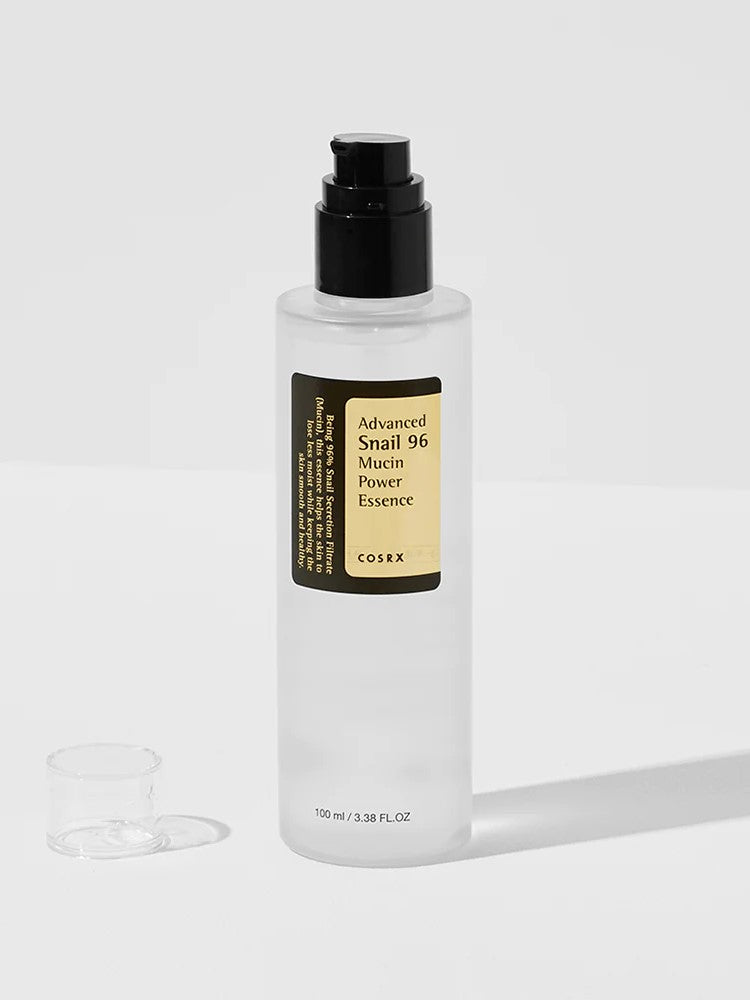 A bottle of Cosrx Advanced Snail 96 Mucin Power Essence with a black pump beside its small transparent cap on a light background.