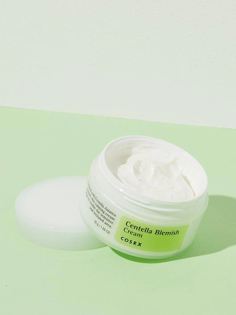 Opened jar of Cosrx Centella Blemish Cream, highlighting its smooth, creamy texture, set against a pastel green background for soothing skincare.