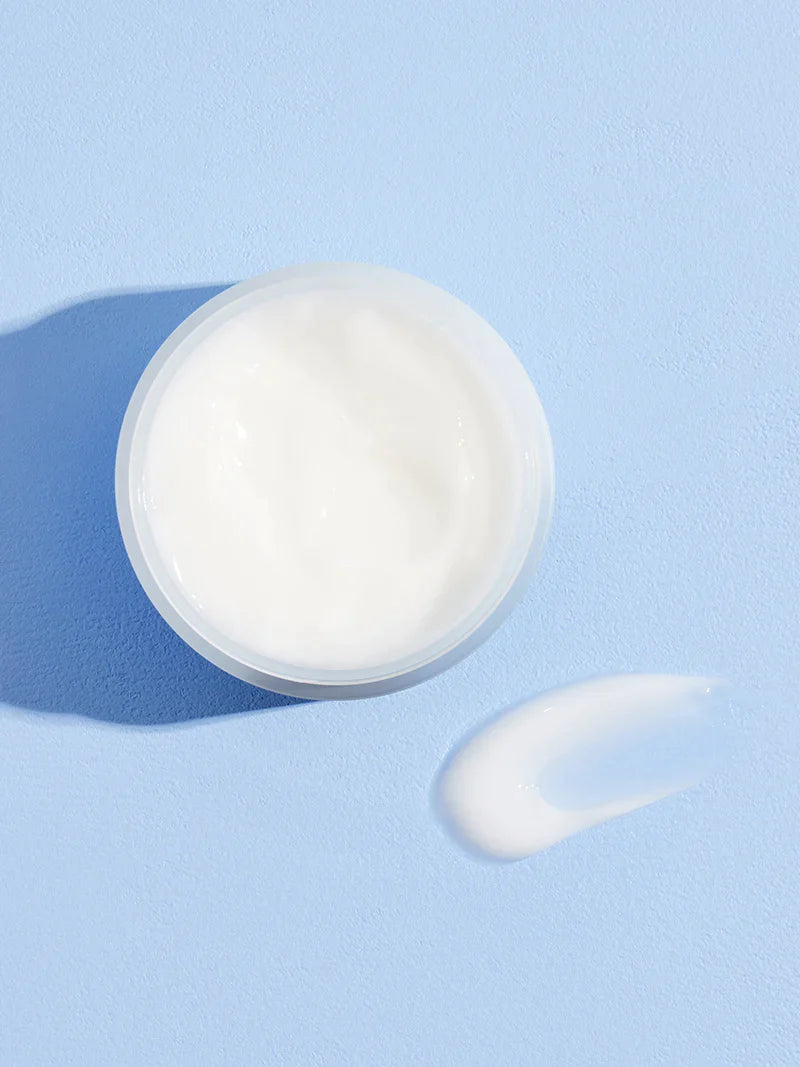 Cosrx Hyaluronic Acid Intensive Cream on a pastel blue surface, with a small blob of cream showcasing its smooth texture.
