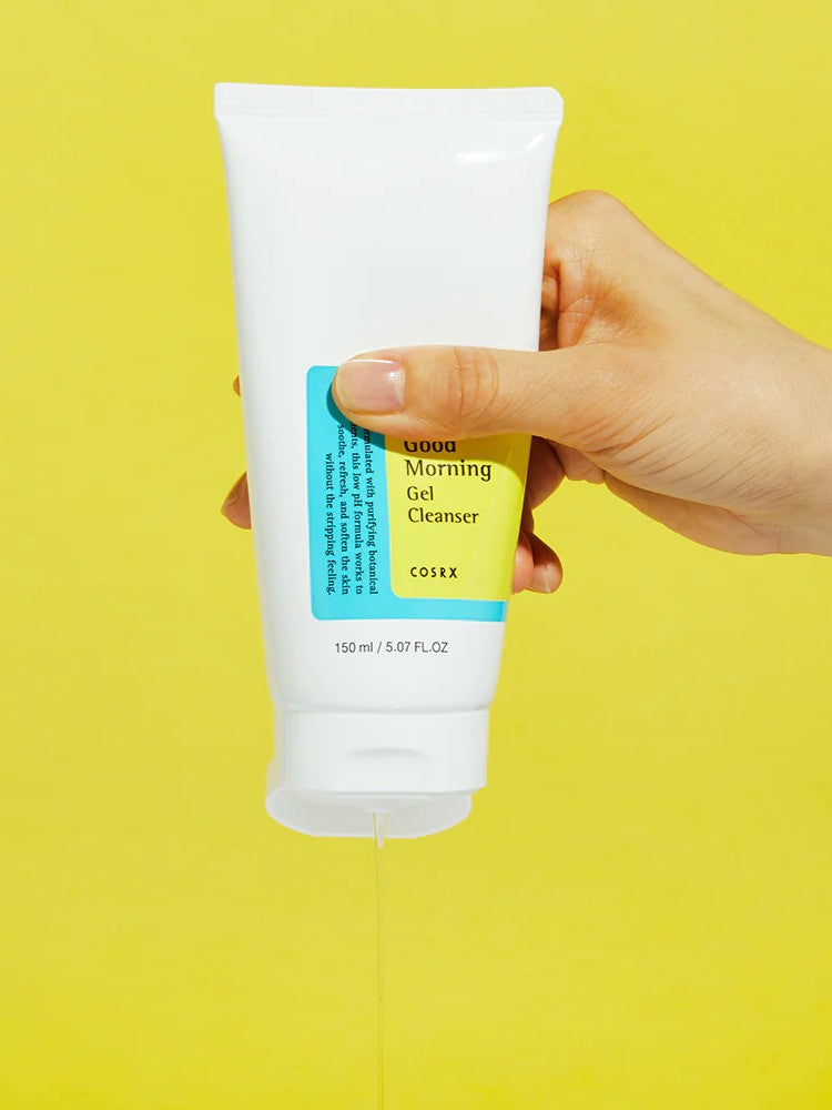 A hand holds a tube of Cosrx Low pH Good Morning Gel Cleanser, pouring gel onto a bright yellow background.