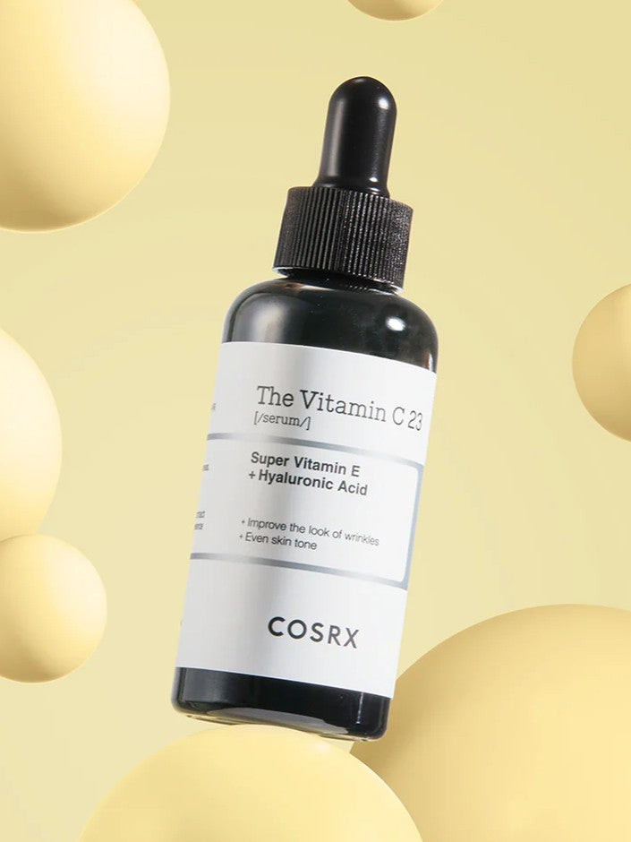Black dropper bottle of Cosrx The Vitamin C 23 Serum against a soft yellow background, highlighting its skin benefits.