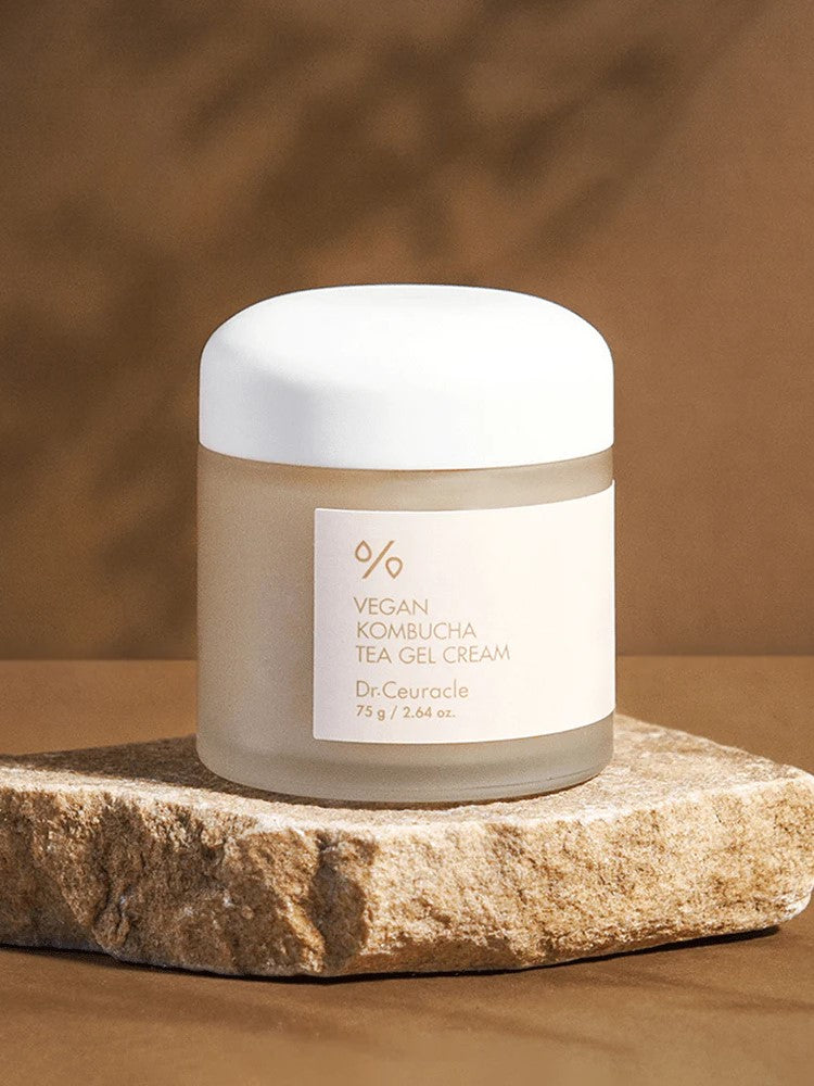 A jar of Dr. Ceuracle Vegan Kombucha Tea Gel Cream on a stone surface, with a warm, blurred background highlighting its lightweight and hydrating formula.