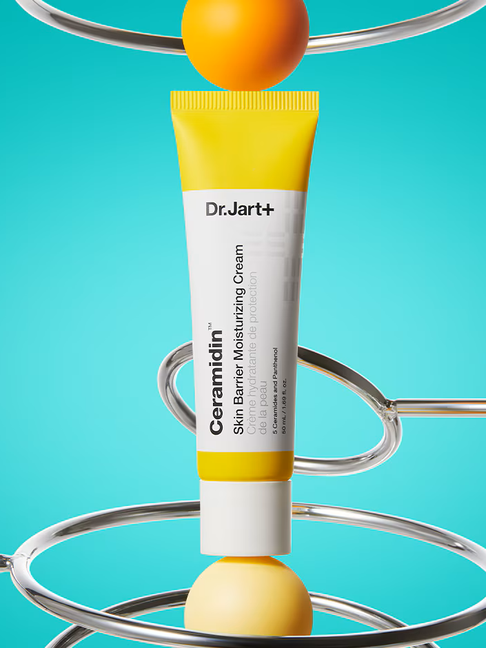 Dr. Jart+ Ceramidin Skin Barrier Moisturizing Cream displayed upright between metallic loops on a vibrant blue background.