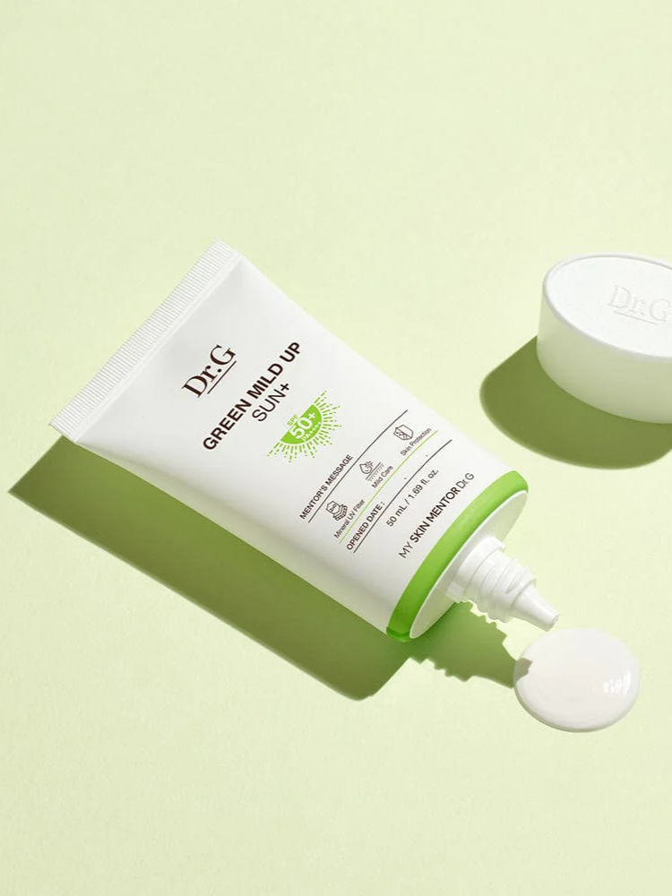 Dr.G Green Mild Up Sun+ Sunscreen tube dispensing a dollop of cream onto a light green background, highlighting its creamy yet lightweight texture.