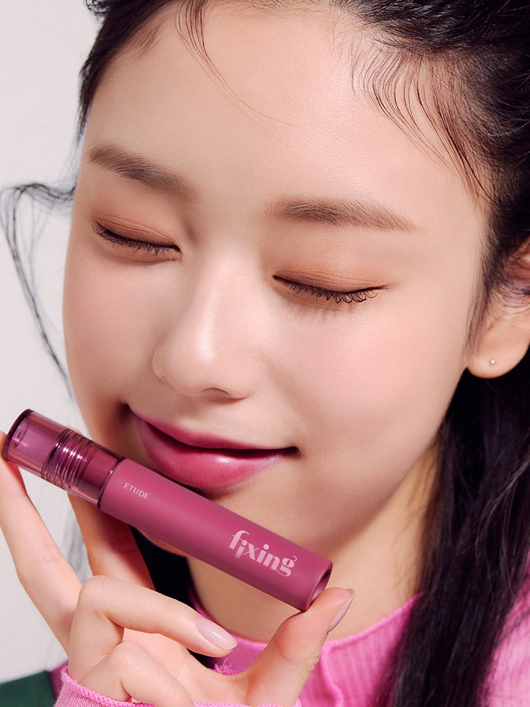 A model holds a lipstick from the Etude House Fixing Tint Collection, showcasing the texture on her lips.