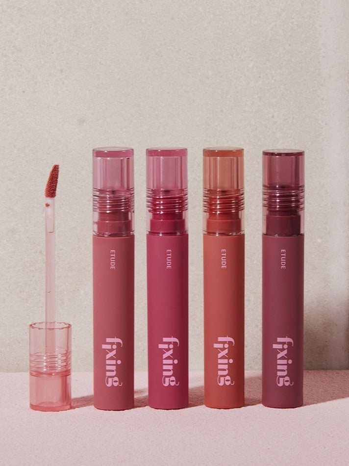 Four lip products in pink and coral shades from the Etude House Fixing Tint Collection, with an applicator displayed, arranged against a neutral background.