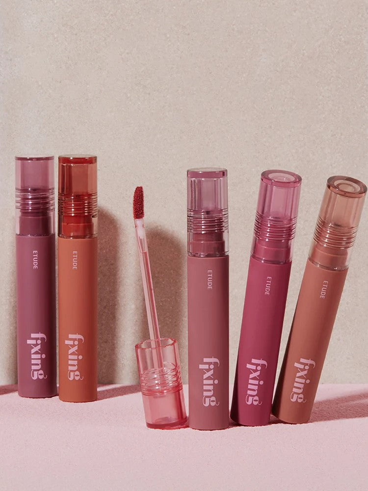 A collection of six Etude House Fixing Tints in shades of pink and nude, displayed against a soft pink backdrop.
