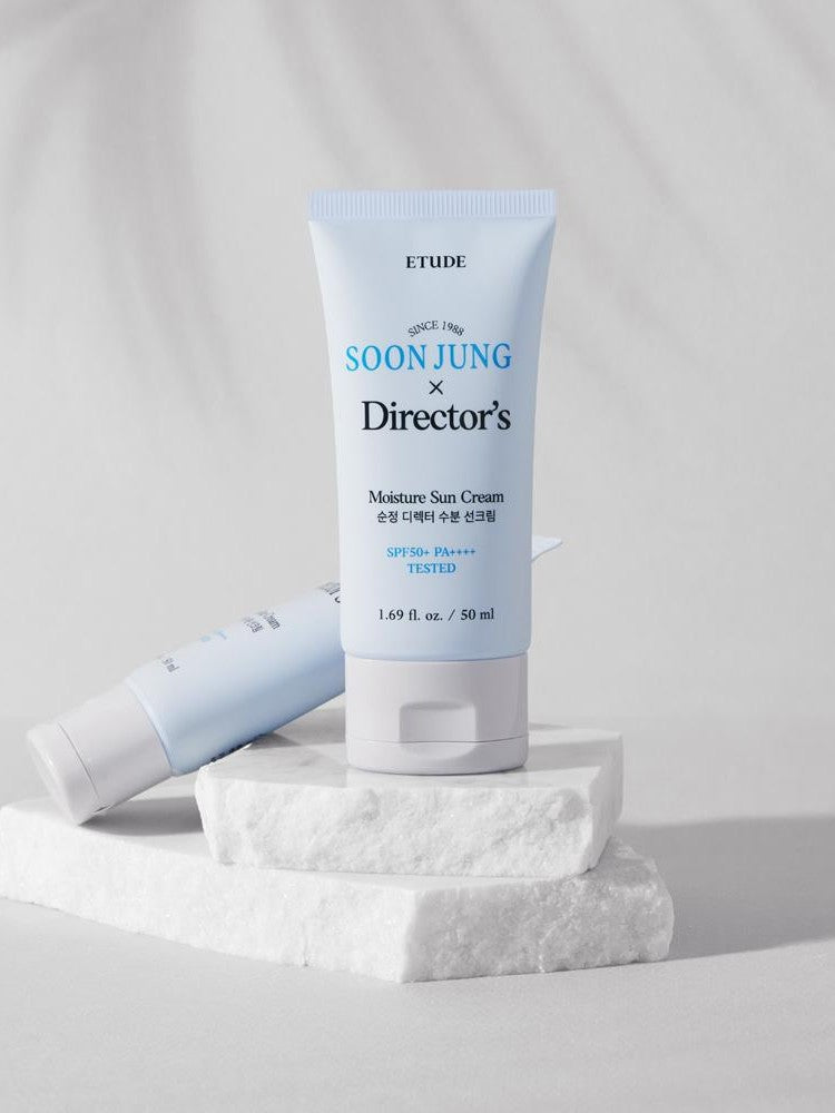 A tube of Etude House Soon Jung Director's Moisture Sun Cream SPF 50+ PA++++, displayed on white marble with a soft gray background.