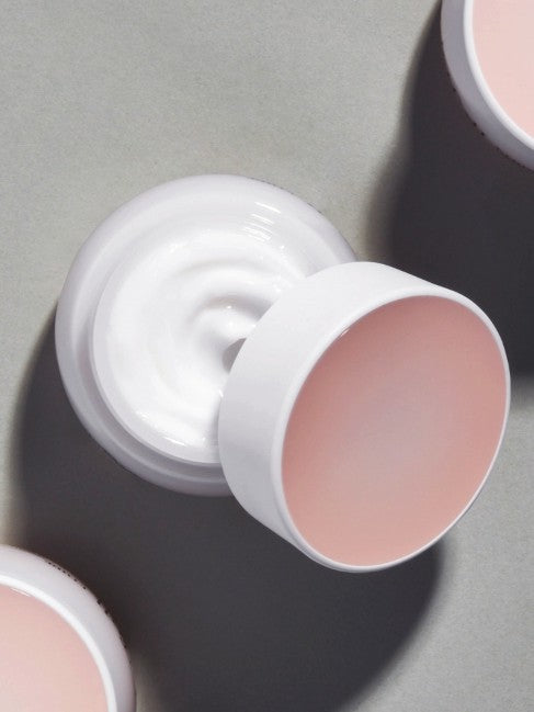 An open jar of Etude Moistfull Collagen Deep Cream, showcasing its creamy white texture and soft pink lid, set against a muted gray background.