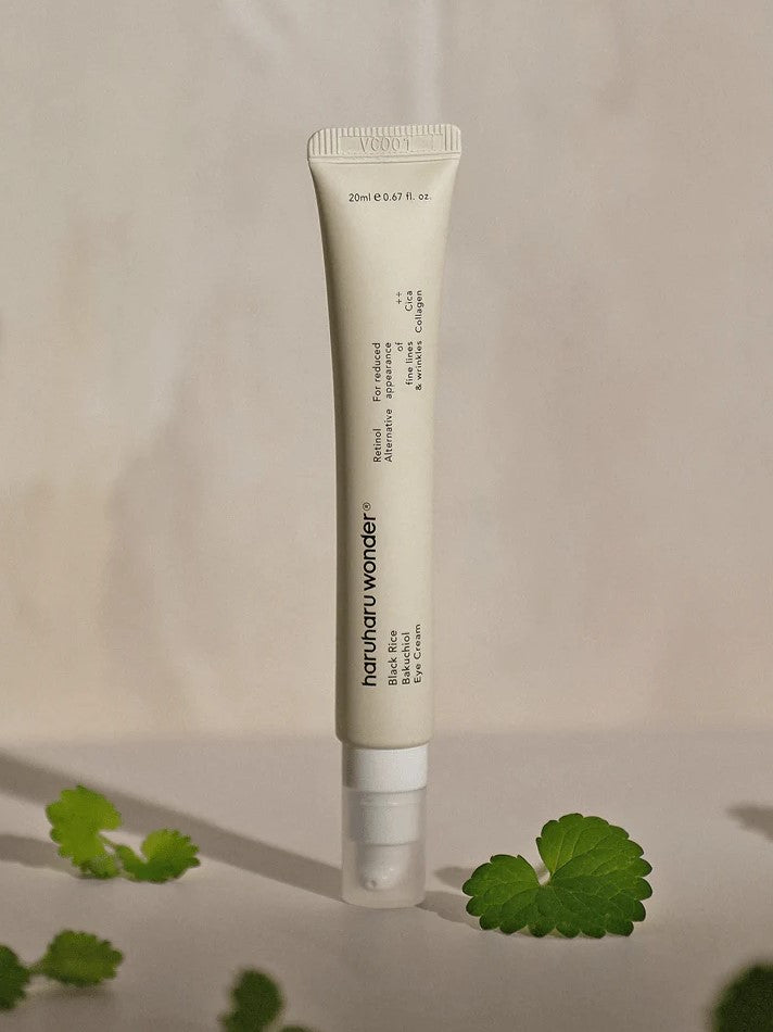 A tube of Haruharu Wonder Bakuchiol Eye Cream set against a soft background with Centella Asiatica leaves nearby, highlighting its soothing ingredients.