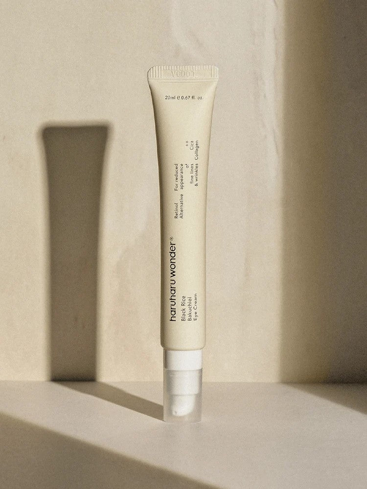A sleek tube of Haruharu Wonder Black Rice Bakuchiol Eye Cream standing on a softly lit surface against a minimalist background.