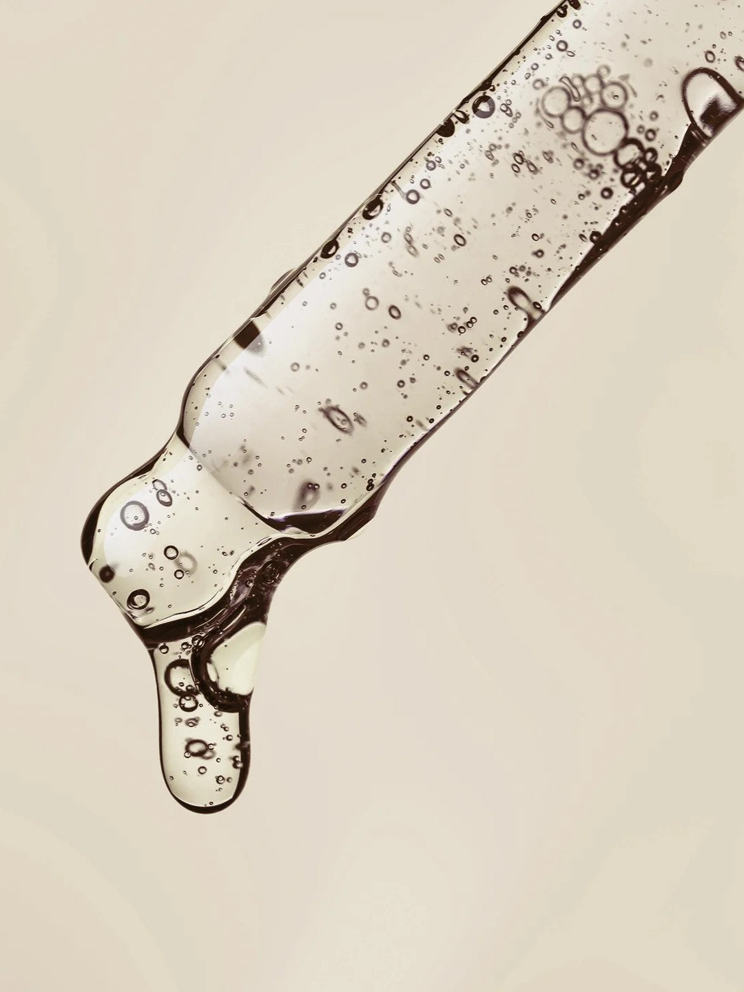 Close-up of Haruharu Wonder Black Rice Hyaluronic Botanical 2GF Wonderful Ampoule dropper releasing clear liquid with tiny bubbles against a soft beige background,