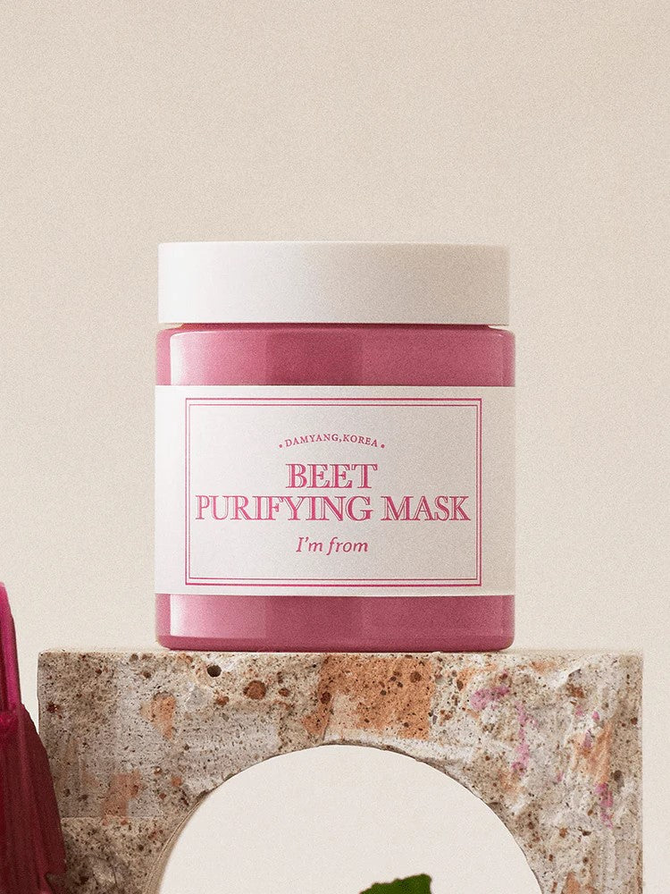 A pink jar of 'I'm From Beet Purifying Mask' displayed on a textured stone pedestal against a soft, neutral background, emphasizing its antioxidant and skin-purifying benefits.