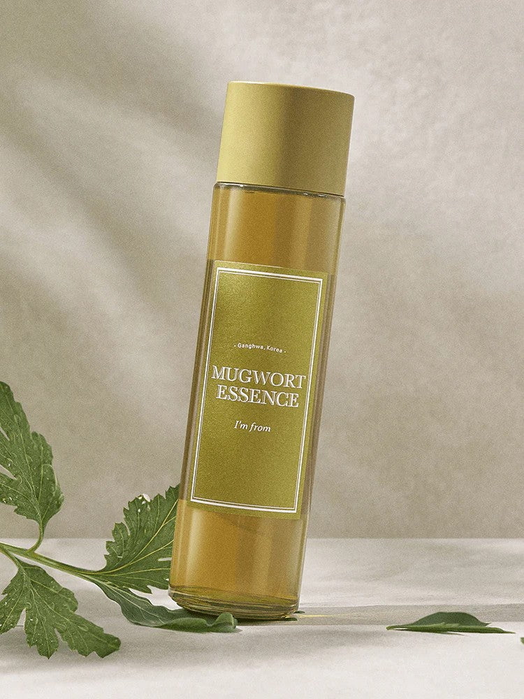 A bottle of 'I'm From' Mugwort Essence set against a soft background, with green Mugwort leaves nearby.