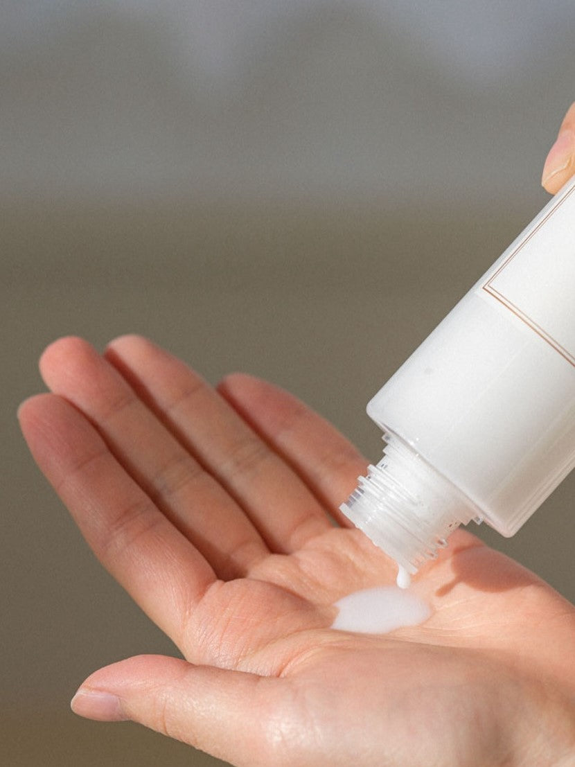 Milky white liquid from the 'I'm From' Rice Toner dripping into a hand held palm.