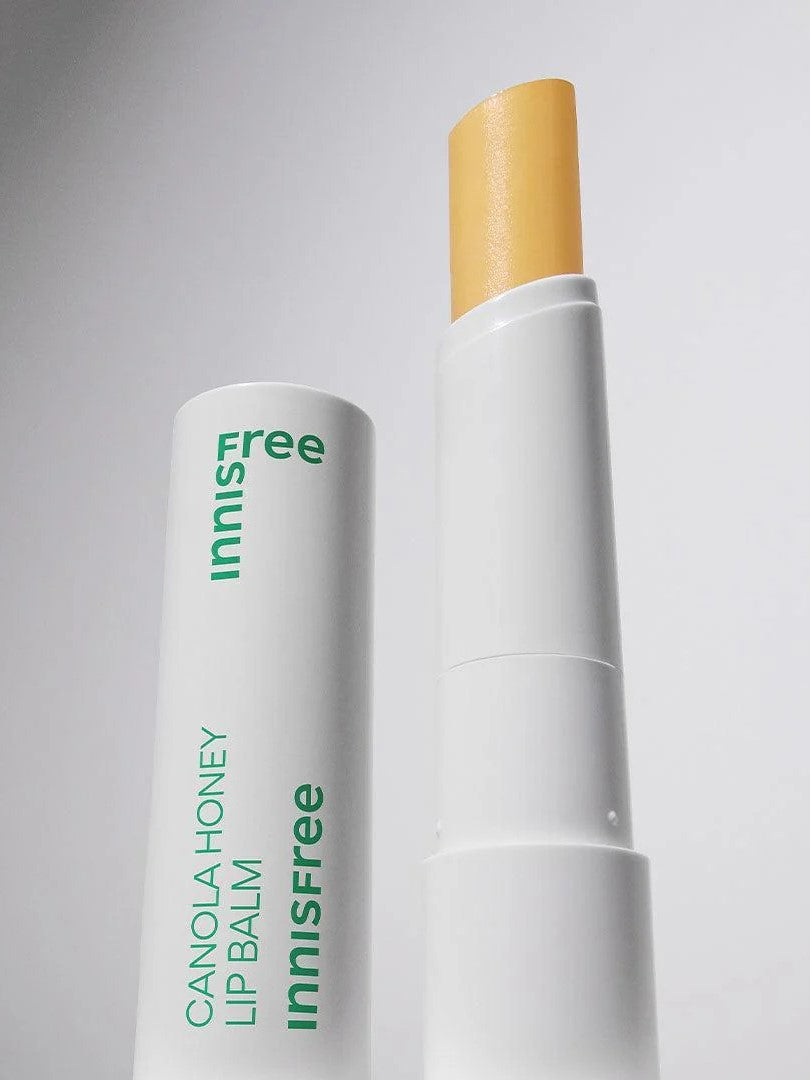 Innisfree Canola Honey Lip Balm with a visible yellow stick, housed in a white container with green lettering, set against a light background.