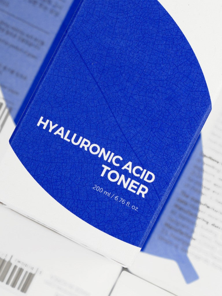 Close-up of the Isntree Hyaluronic Acid Toner's blue packaging, labeled with 200 ml / 6.76 fl. oz., on a white background.