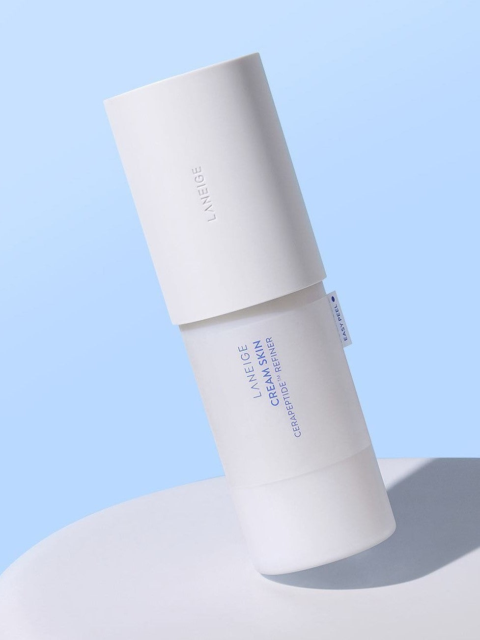 Laneige Cream Skin Cerapeptide™ Refiner resting on a smooth surface against a soft blue backdrop.