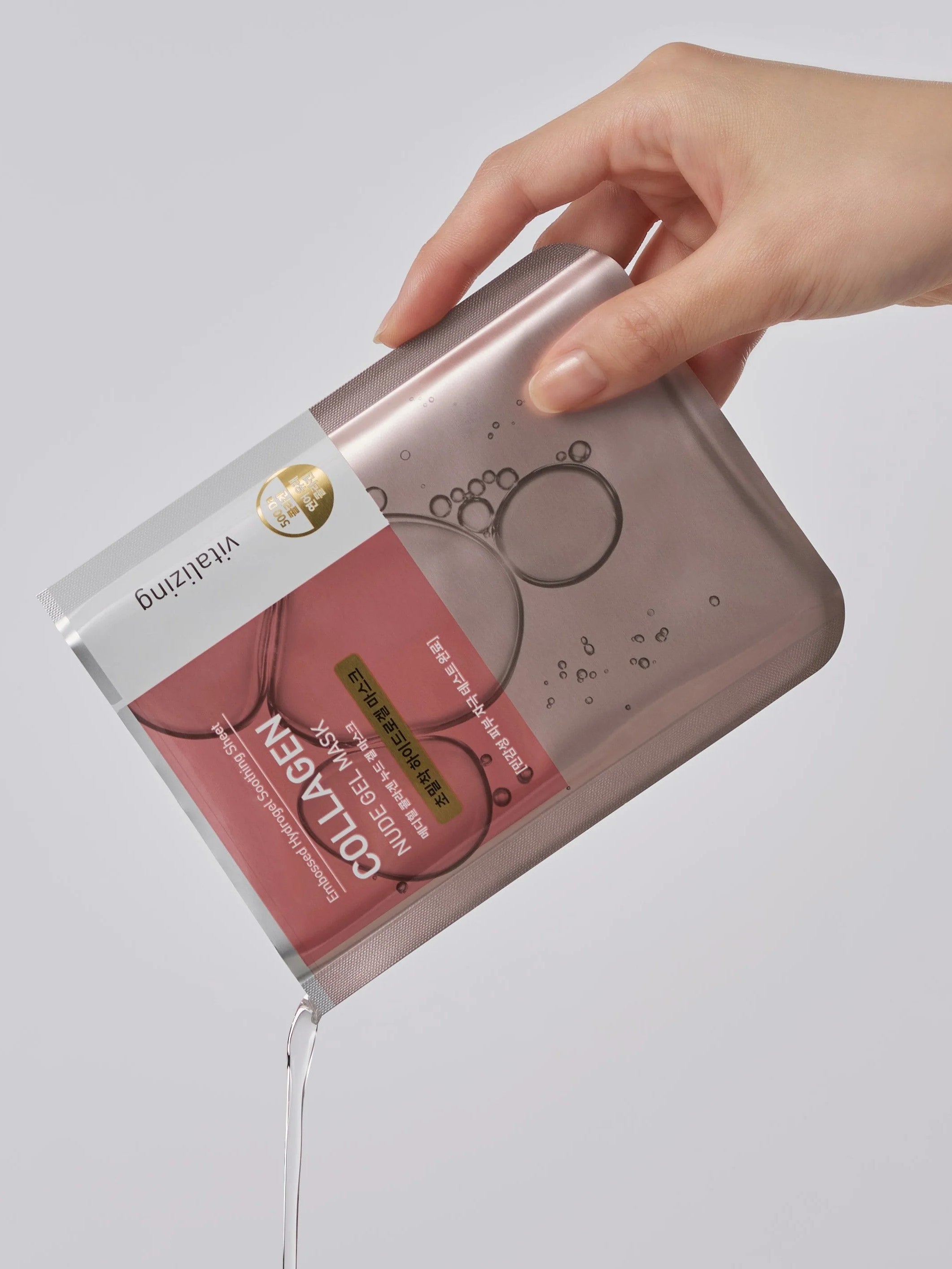 A hand holds the Mediheal Collagen Nude Gel Mask, with essence spilling out, emphasizing its hydrating and nourishing properties.