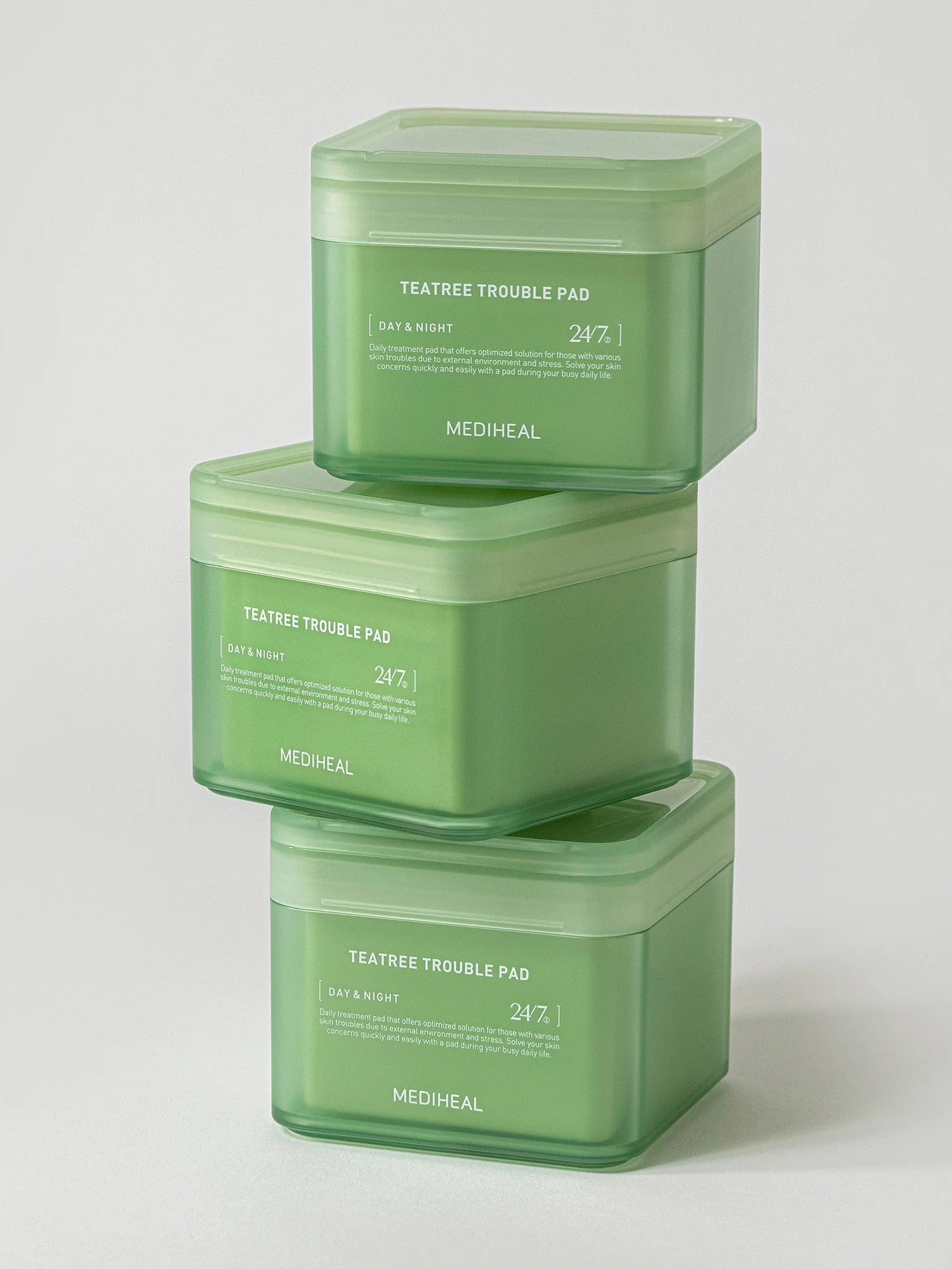 Three stacked green jars of Mediheal Teatree Trouble Pad, designed for day and night use, set against a light gray background.