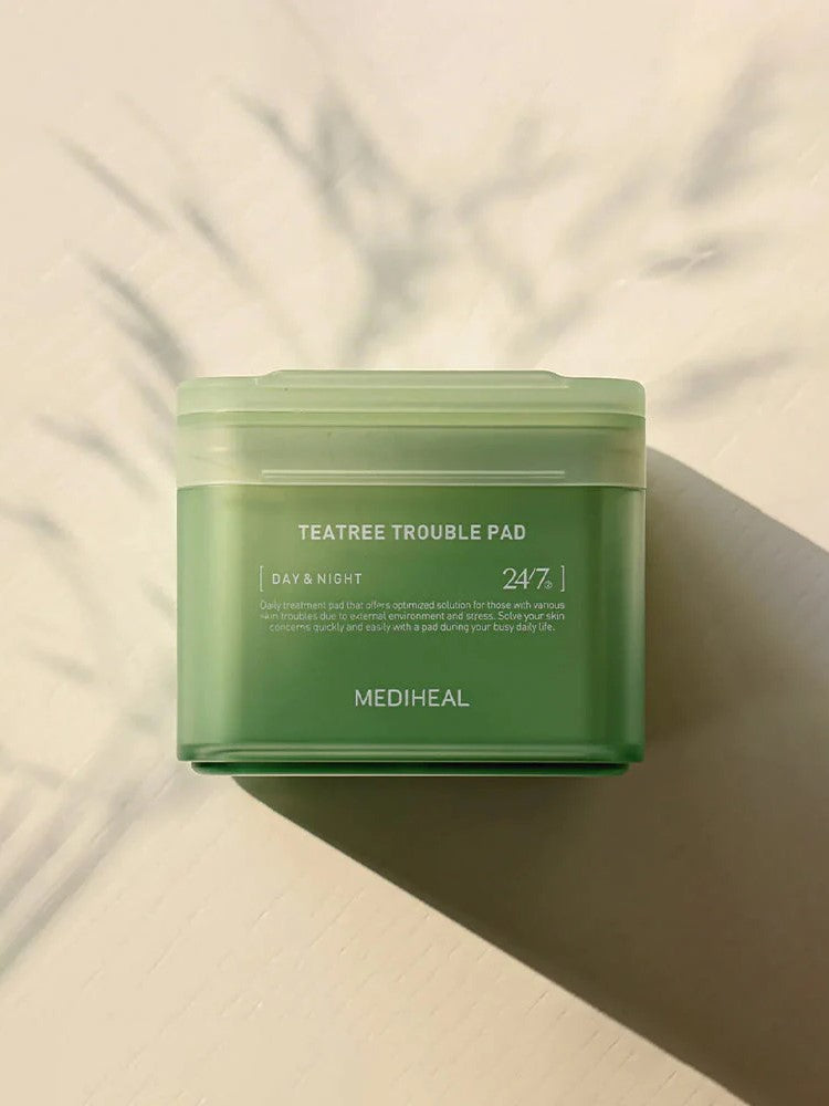 A green jar of Mediheal Teatree Trouble Pad on a light surface, emphasizing its day and night skincare benefits.