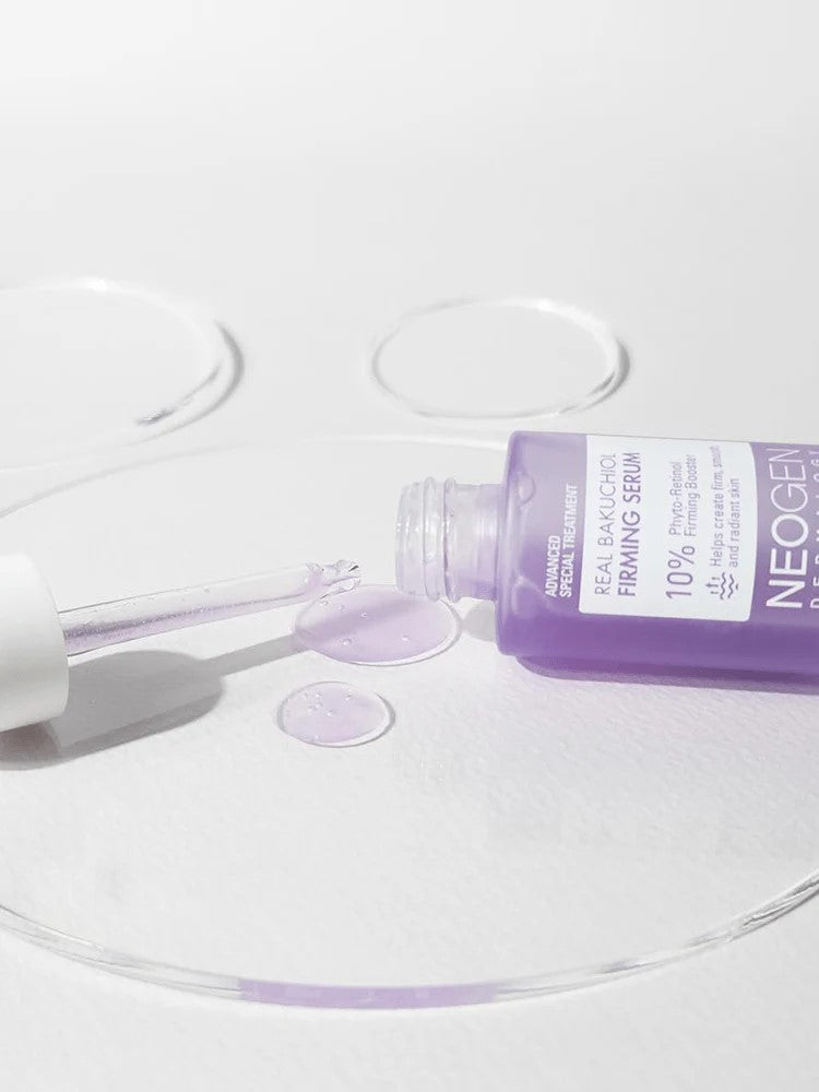 Neogen Bakuchiol Firming Serum bottle with a dropper, spilling vibrant purple liquid onto a white surface, emphasizing its lightweight texture and firming benefits.