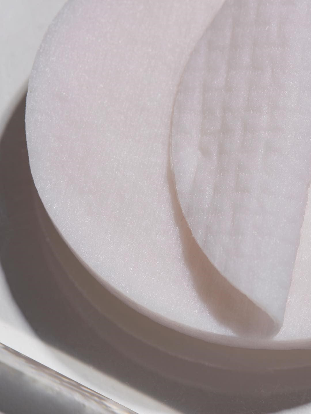 Close-up of white cotton rounds stacked together, highlighting the 100% natural viscose fabric texture of Papa Recipe Eggplant Clearing Peeling Pads.