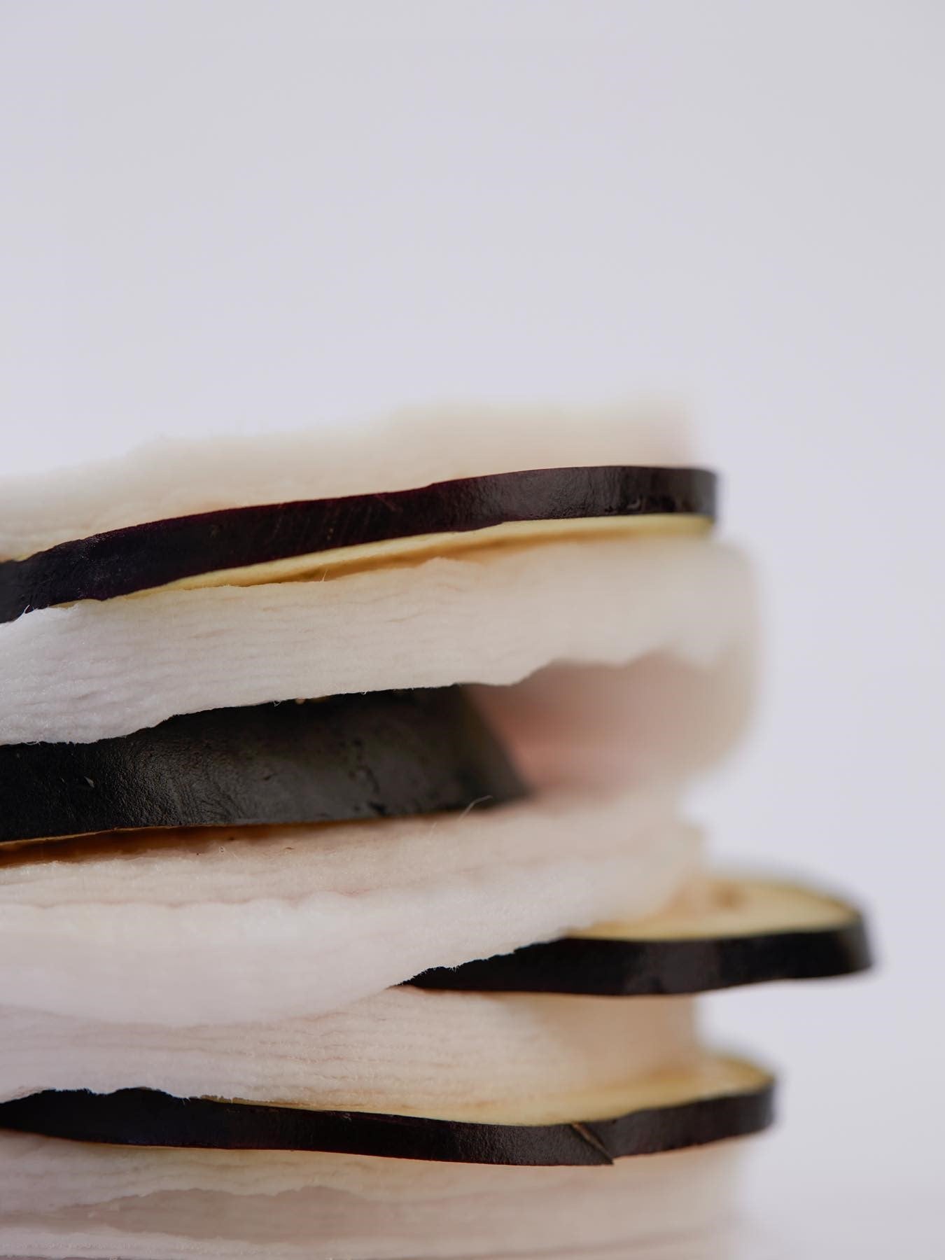 Close-up of Papa Recipe Eggplant Peeling Pads layered with slices of eggplant, showcasing their main ingredient against a white background.