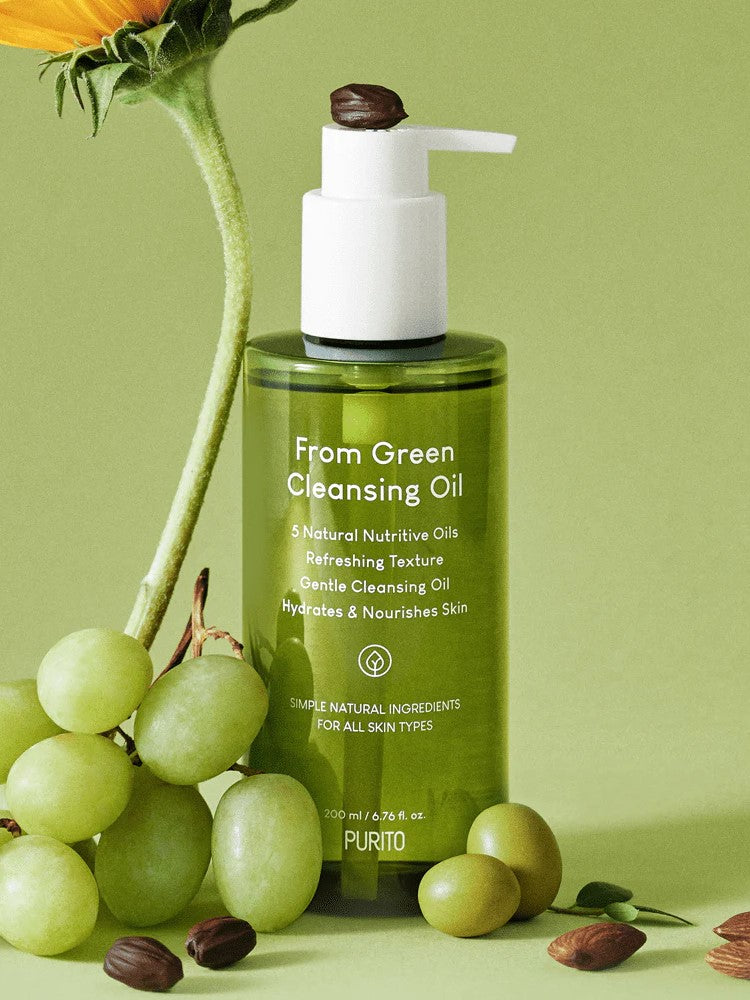 Green bottle of Purito From Green Cleansing Oil surrounded by fresh green grapes, highlighting its natural ingredients and nourishing skincare benefits.