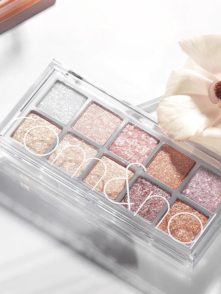 Eyeshadow palette Romand Better Than Palette Light and Glitter Garden, featuring ten shimmering shades from silver to pink and rose gold, styled with a delicate flower.