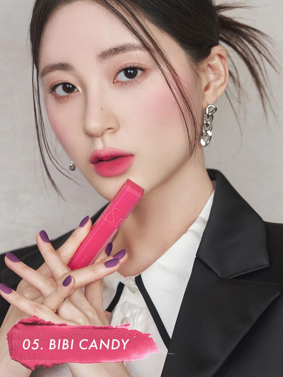 A model wearing Romand Blur Fudge Tint in the shade Bibi Candy, showcasing the soft matte texture on her lips.