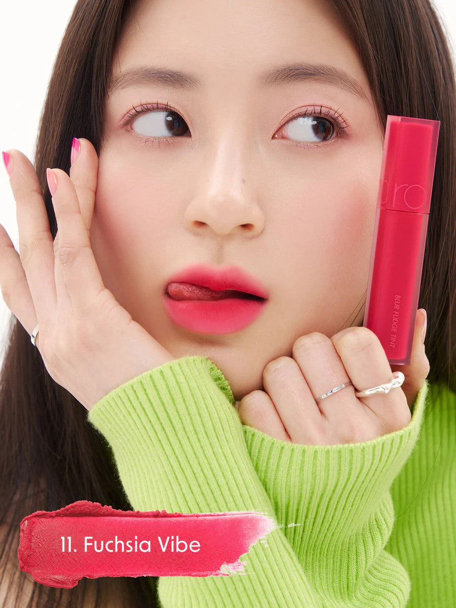 A model wearing Romand Blur Fudge Tint in the shade Fuchsia Vibe, showcasing the soft matte texture on her lips.