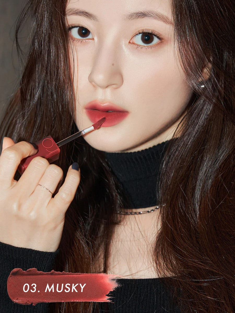 A model wearing Romand Blur Fudge Tint in the shade Musky, showcasing the soft matte texture on her lips.