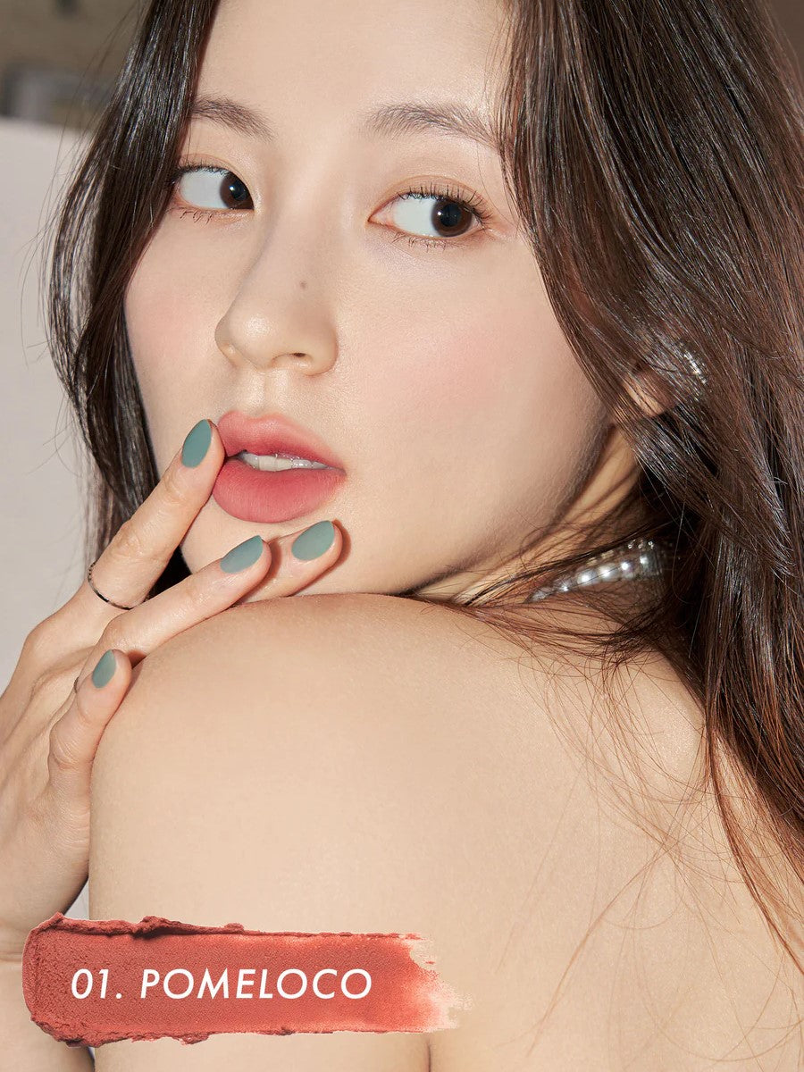 A model wearing Romand Blur Fudge Tint in the shade Pomeloco, showcasing the soft matte texture on her lips.