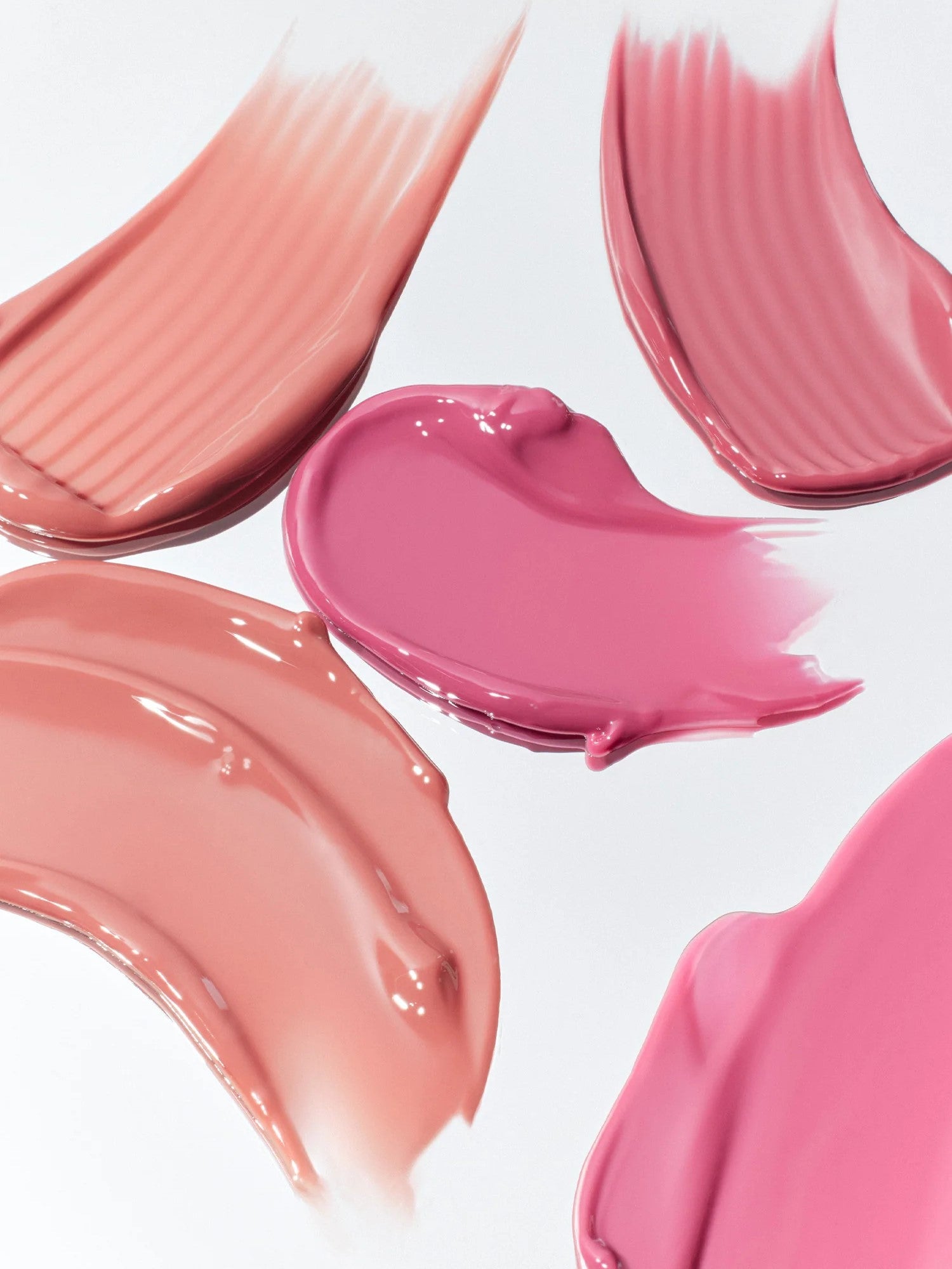 Smooth swatches of pink and nude shades from Romand Glasting Color Tint, displayed on a white background to show glossy textures and finishes.