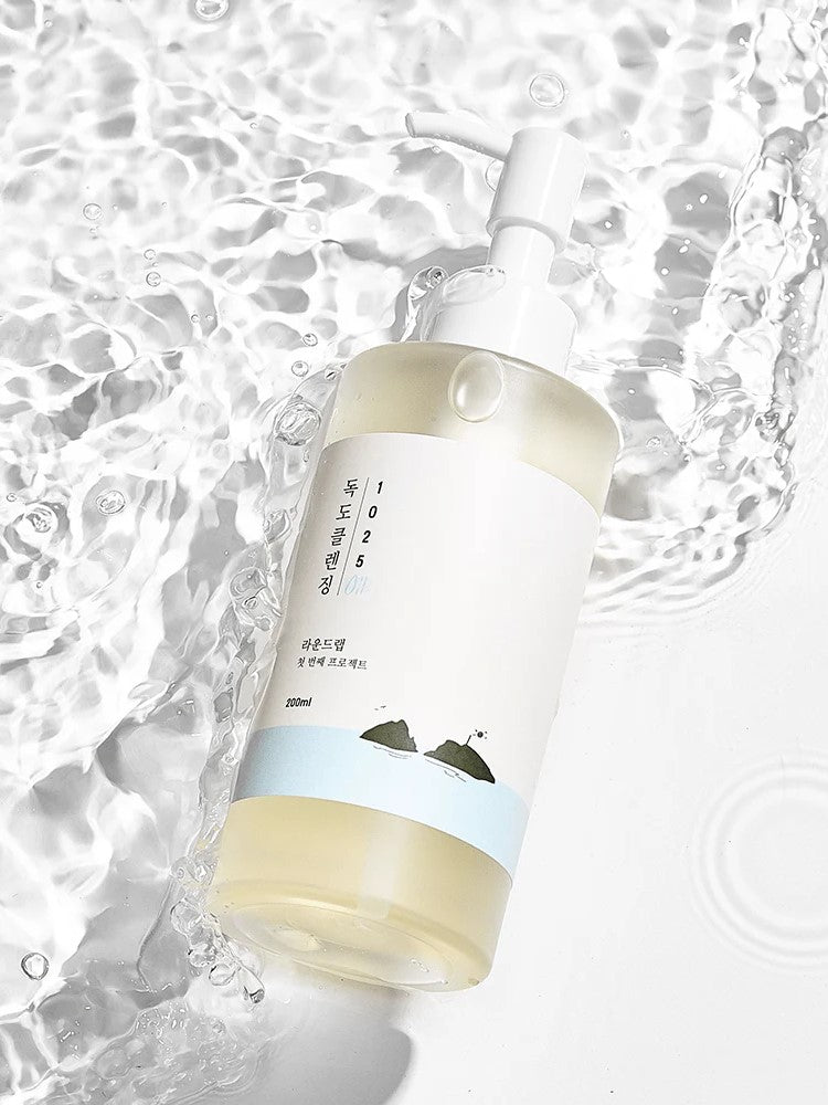 Round Lab 1025 Dokdo Cleansing Oil partially submerged in water, featuring a minimalist design and nature-inspired artwork.