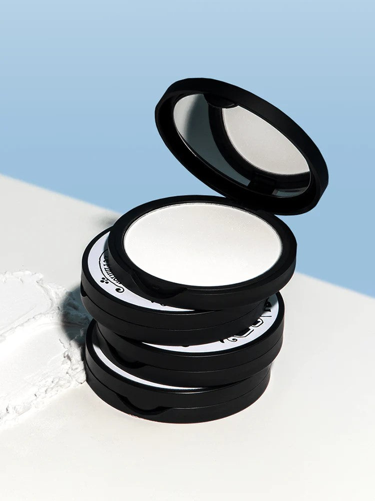 A stack of four Too Cool for School Artclass By Rodin Finish Setting Pact cases, with one case open to reveal the smooth white powder inside, displayed against a soft blue background.