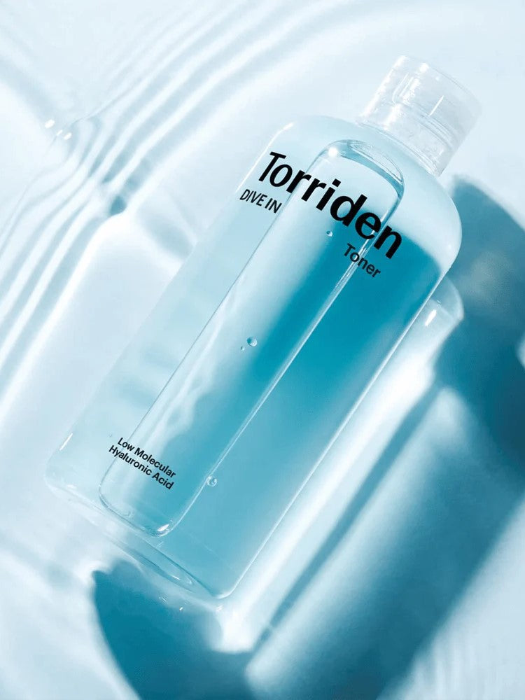 Clear toner bottle labeled 'Torriden Dive In' with 'Low Molecular Hyaluronic Acid,' sitting on wavy blue water background.