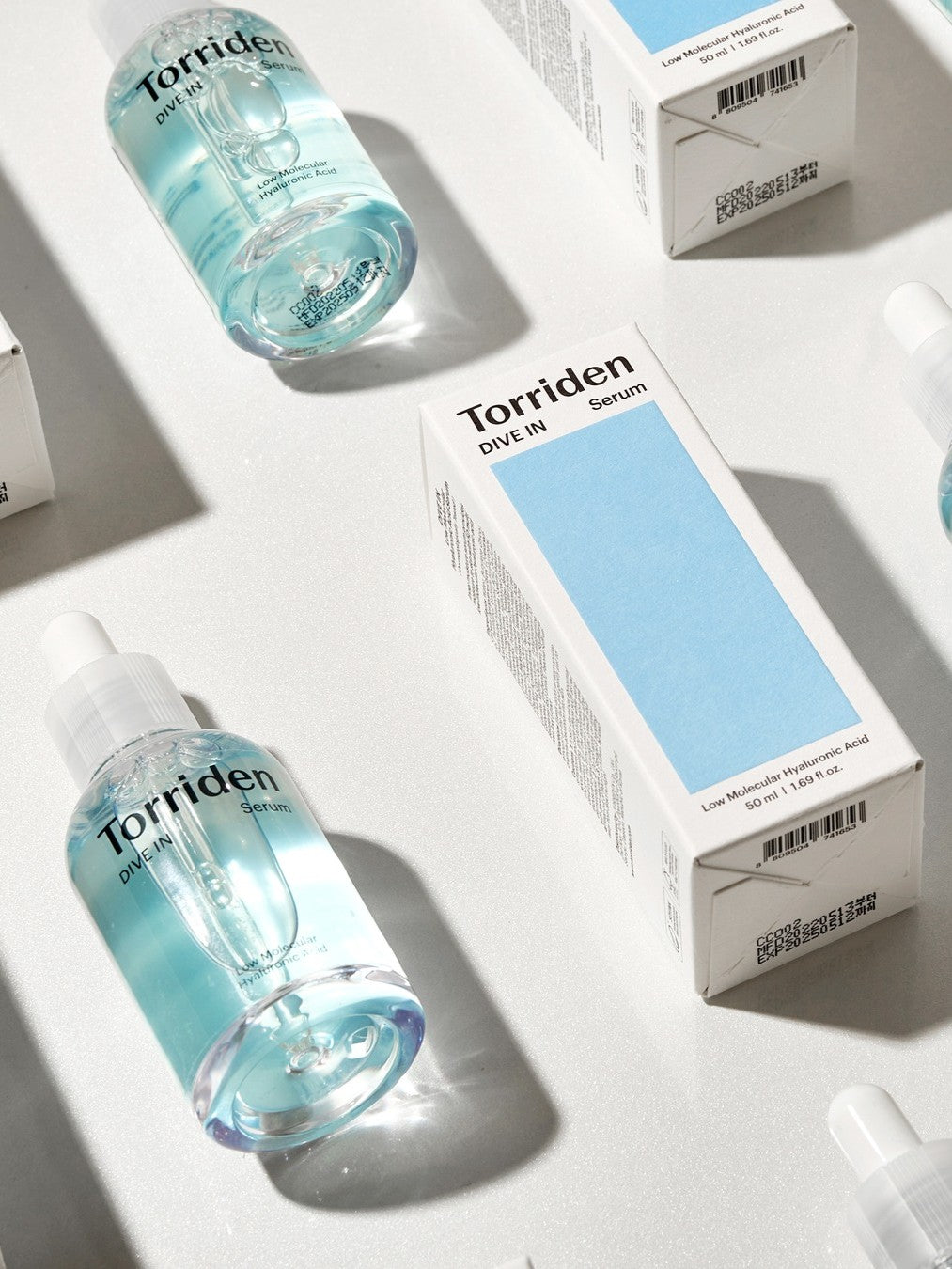 Two Torriden Dive In serum bottles with light blue liquid alongside their boxes featuring black text, emphasizing an instant boost of hydration.